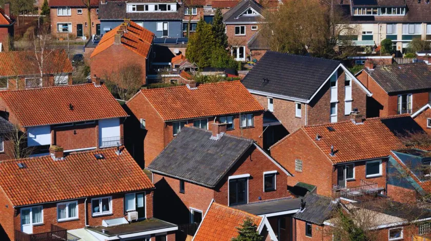 Bovenaanzicht van verschillende huizen met donkere en rode pannendaken
