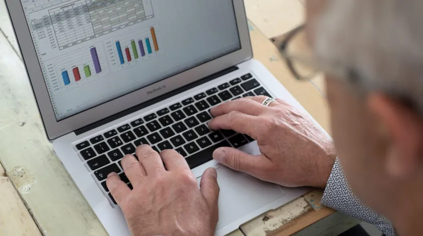 Man met bril achter laptop, op het scherm staan grafieken
