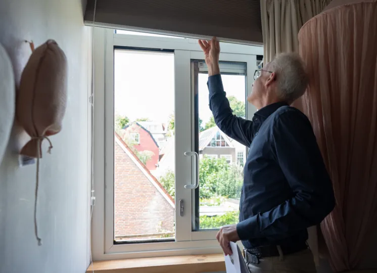 Man in raamkozijn bezig met rolgordijn