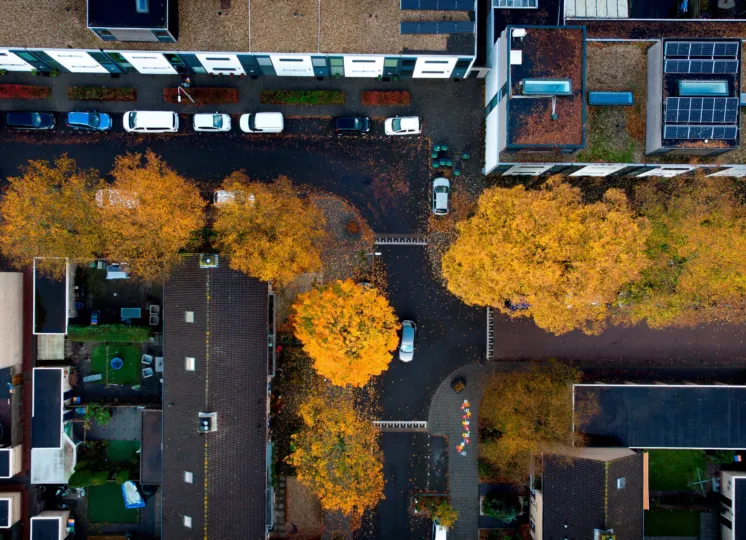 Bovenaanzicht van een wijk met flatgebouwen en bomen.