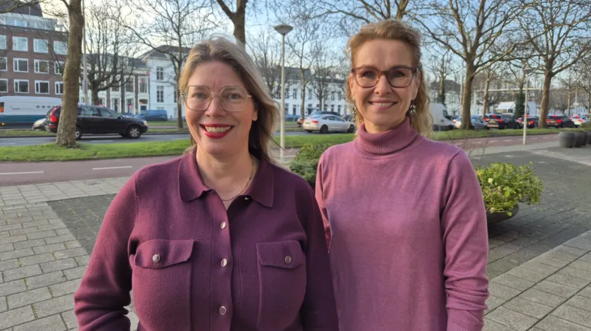Portretfoto van 2 vrouwen op een stoep met bomen en auto's