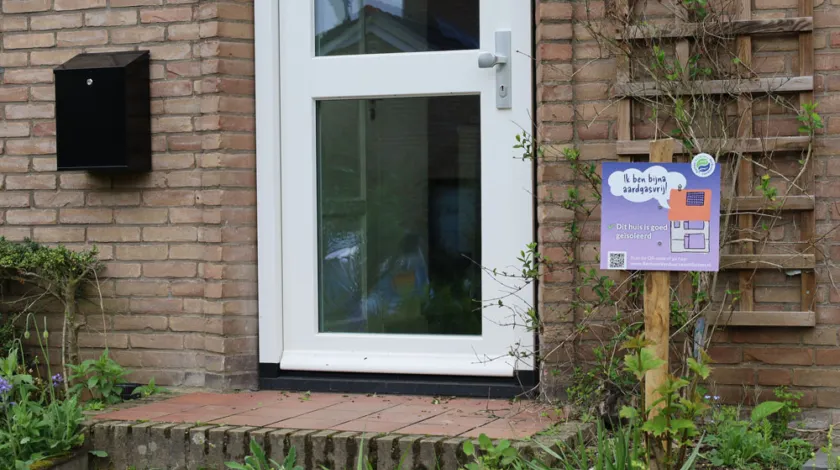 Een bordje naast de voordeur met daarop de tekst 'Ik ben bijna aardgasvrij!'