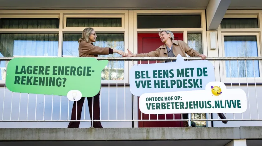 Elanor Boekholt-O'Sullivan en Ika van de Pas schudden elkaar de hand op het balkon van een flat.