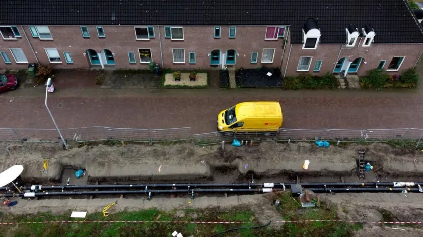 Een straat waar de stoep is uitgegraven om er buizen in te leggen voor een warmtenet.