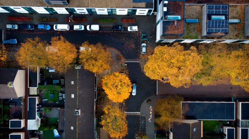 Bovenaanzicht van een wijk met flatgebouwen en bomen.