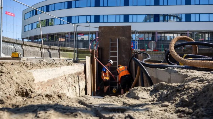 2 bouwvakkers met oranje hesjes aan het werk in de bodem
