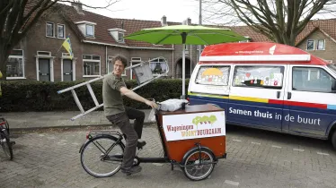 Man met ladder op bakfiets voor een klusbus