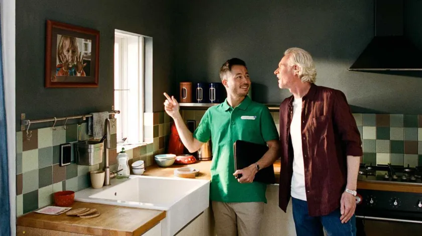 Man in groen shirt (energieklusser) adviseert een oudere manier in zijn keuken