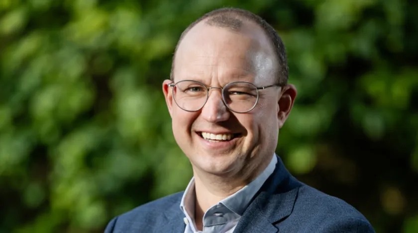 Portretfoto van man in pak voor een groene struik