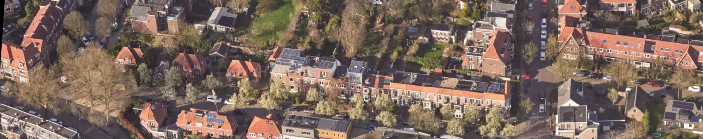 Luchtopname van een groene wijk met oudere huizen met rode pannendaken