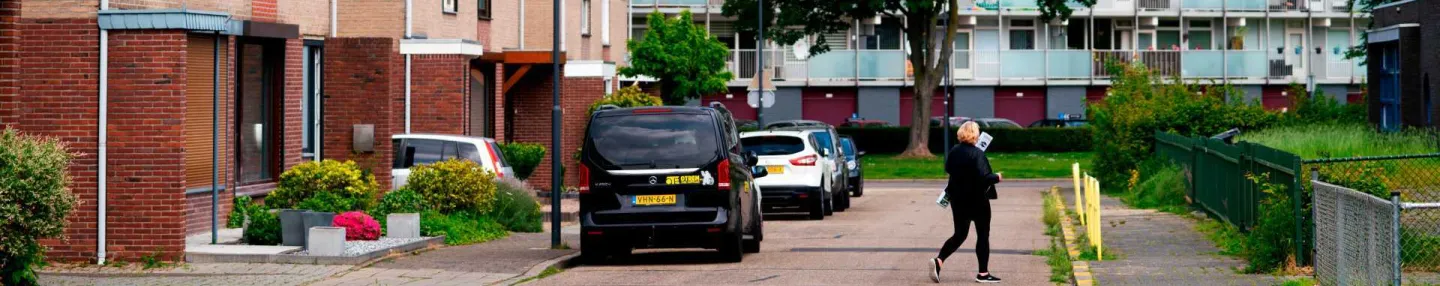 Straat met laagbouw met uitzicht op een hoge galerijflat