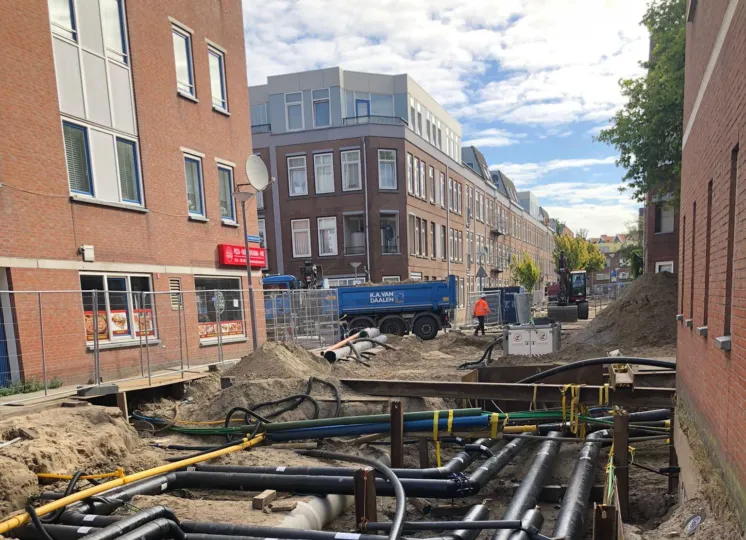 Opengebroken straat met zwarte leidingen voor aansluiting op het warmtenet