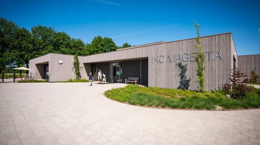 Modern houten schoolgebouw met schoolplein ervoor