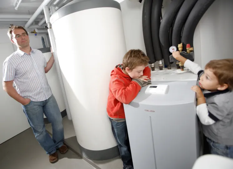 Twee kinderen kijken naar een nieuwe warmtepomp terwijl hun vader toekijkt.