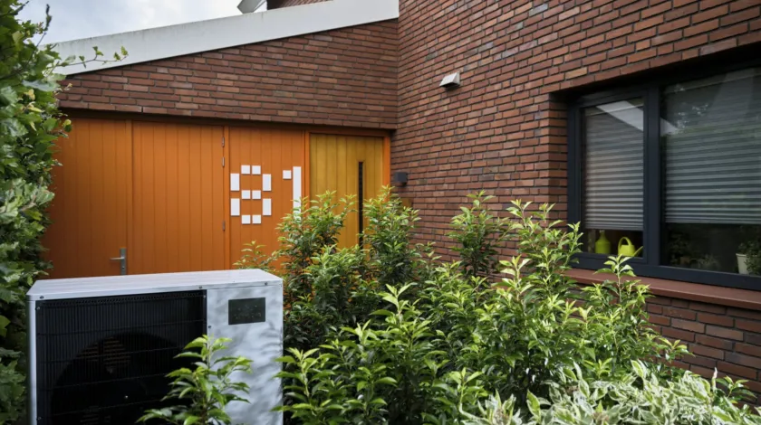 Buitenunit van een warmtepomp in de tuin van een huis